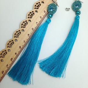 Peut inclure: Une paire de boucles d'oreilles à franges bleu turquoise avec un design en perles et en fil. Les boucles d'oreilles mesurent environ 15 cm de long.