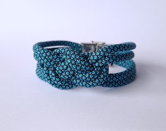 585. Bracelet en paracorde turquoise/bleu à motifs noirs avec tressage noeud marin