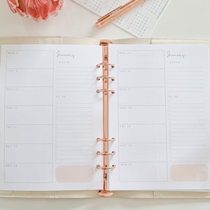 May include: A white planner with a rose gold binding. The planner has a weekly layout with space for notes and to-do lists. The planner is open to the week of 8th January to 14th January.