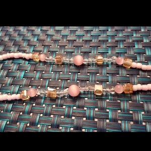 Puede incluir: Un collar de cuentas rosa y blanco con cuentas transparentes y doradas. El collar tiene un patrón repetitivo de rosa, transparente, dorado, transparente, rosa, transparente, dorado, transparente, rosa.