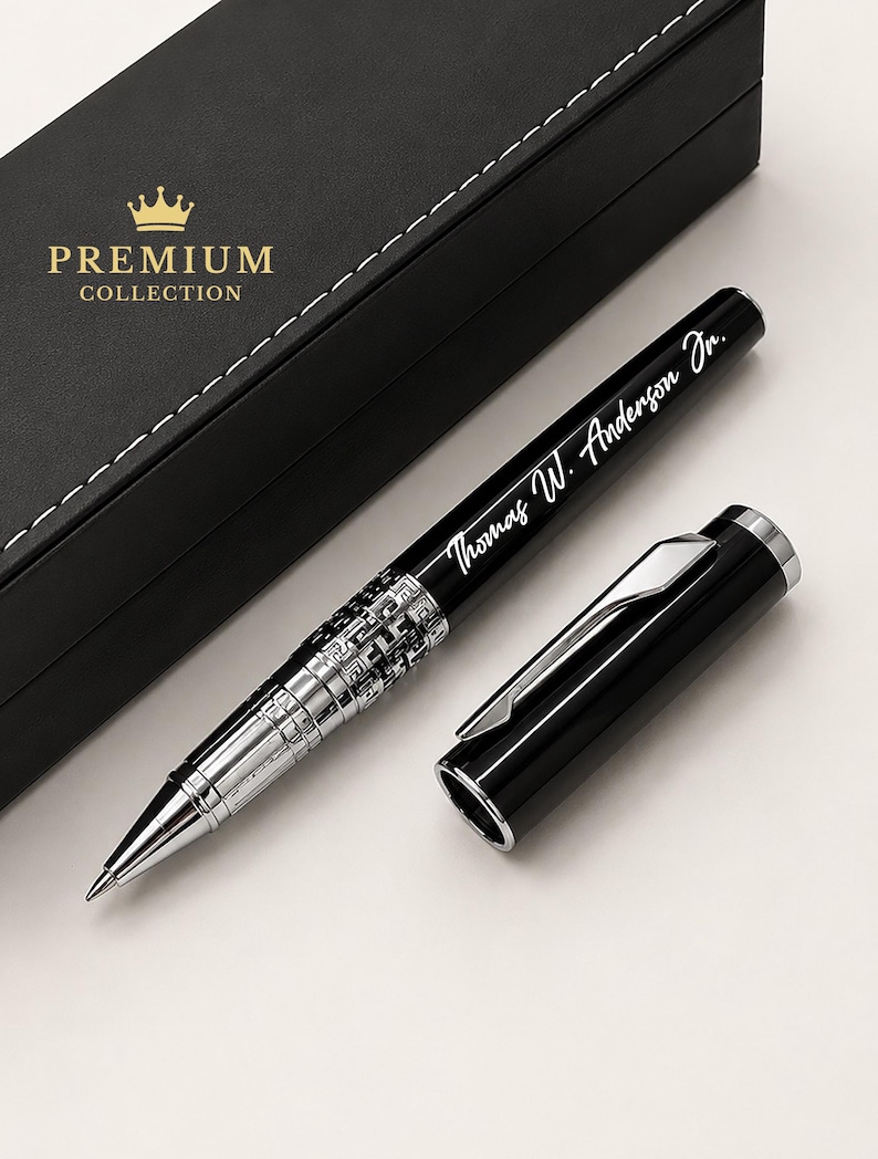 Puede incluir: Un bol&iacute;grafo negro con detalles plateados y el nombre grabado "Thomas W. Anderson Jr." se muestra junto a su tapa. El bol&iacute;grafo se presenta con una caja negra que tiene las palabras "PREMIUM COLLECTION" en letras doradas.
