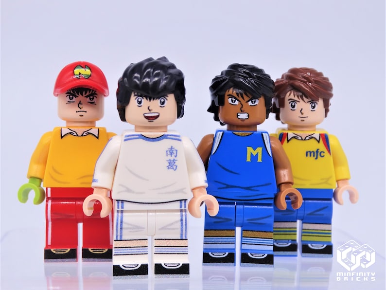 May include: Four minifigure toys of soccer players wearing different uniforms. The players are wearing red, white, blue, and yellow jerseys. The players have different hairstyles and facial expressions. The minifigures are standing on a white surface.