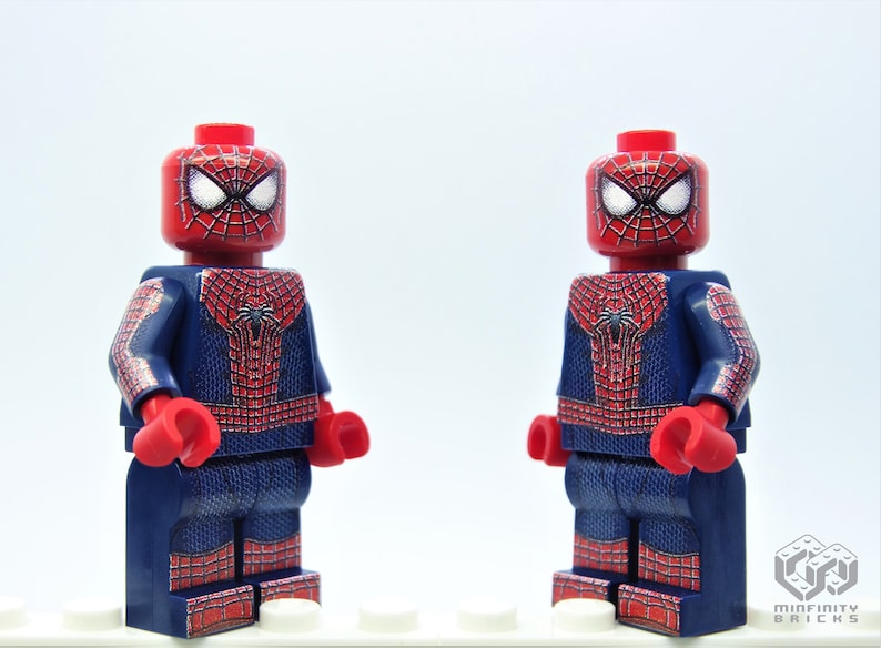 K&ouml;nnte beinhalten: Zwei Lego-Minifiguren von Spider-Man. Sie haben rote K&ouml;pfe mit wei&szlig;en Augen und Spinnennetzmustern. Die Kost&uuml;me sind blau mit roten Spinnennetzdesigns, roten Handschuhen und Stiefeln.