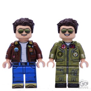 Puede incluir: Dos minifiguras Lego de un hombre que lleva diferentes atuendos. La minifigura de la izquierda lleva una chaqueta de cuero marr&oacute;n con parches, pantalones vaqueros azules y gafas de sol. La minifigura de la derecha lleva un traje de vuelo verde con parches y gafas de sol.