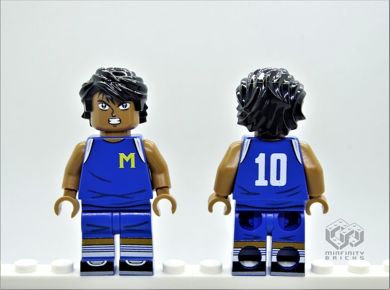 May include: A blue and white basketball jersey with the letter "M" on the front and the number "10" on the back. The jersey is worn by a Lego minifigure with black hair and brown skin.