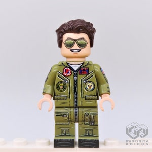 Puede incluir: Una minifigura Lego de un piloto que lleva un traje de vuelo verde con parches y gafas de sol. La minifigura tiene el pelo casta&ntilde;o y una cara sonriente.
