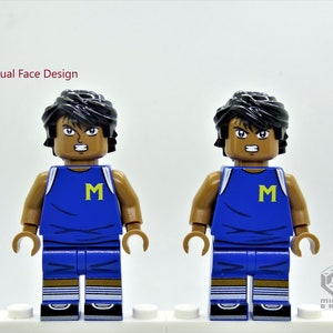 May include: Dual Face Design. A Lego minifigure with black hair, brown skin, and a blue basketball jersey with a yellow "M" on the front. The minifigure has two different facial expressions.
