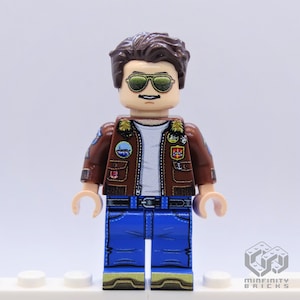 Puede incluir: Una minifigura de Lego que lleva una chaqueta de cuero marr&oacute;n con parches, pantalones vaqueros azules y gafas de sol. La minifigura tiene el pelo casta&ntilde;o y un bigote.