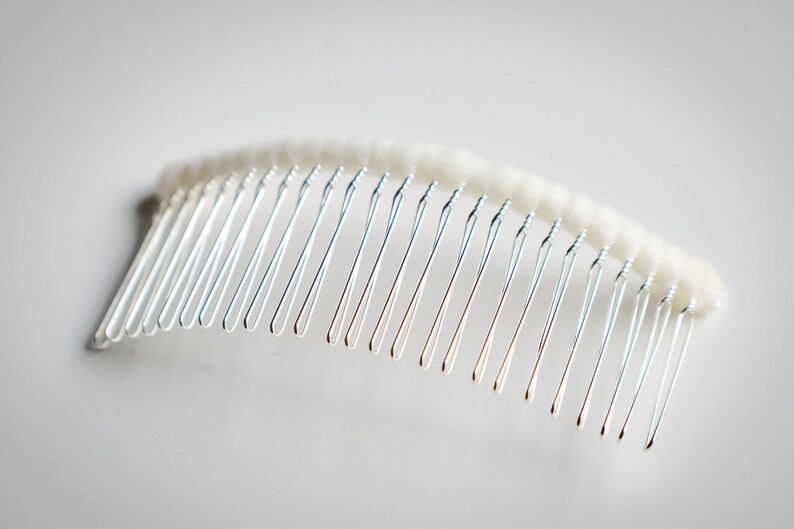 May include: A silver hair comb with a white, fluffy, padded base.