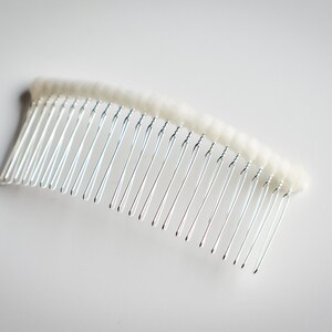 May include: A silver hair comb with a white, fuzzy, padded base.