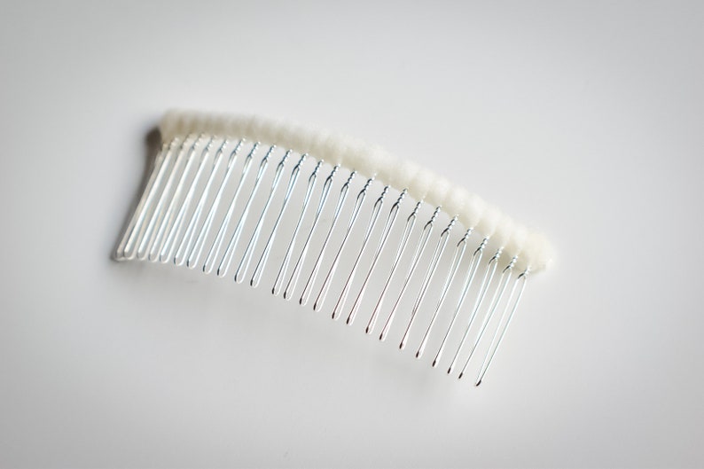 May include: A silver hair comb with a white, fuzzy, padded base.