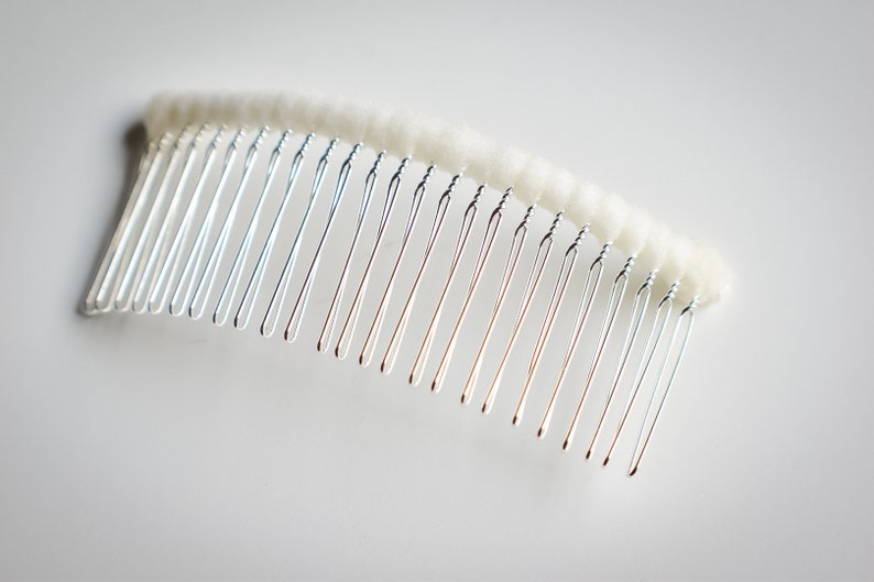 May include: A silver hair comb with a white, fluffy, padded base.