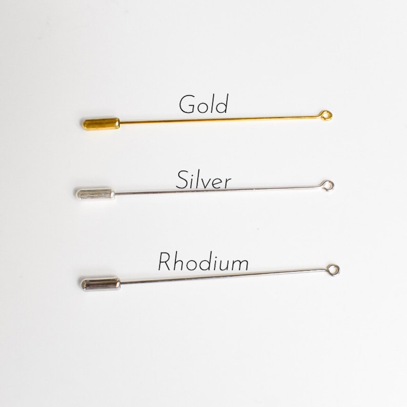 May include: Three metal lapel pins in gold, silver, and rhodium. Each pin has a straight, slender body with a rounded end and a small loop at the opposite end. The word "Gold", "Silver", and "Rhodium" are written above each pin.