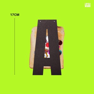 May include: Black letter A cut out of paper, shaped like a slice of bread with colorful confetti inside. The letter is 17 inches tall.