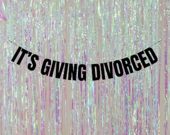Könnte beinhalten: Ein schwarzes Banner mit dem Text "IT'S GIVING DIVORCED" hängt vor einem schimmernden, regenbogenfarbenen Hintergrund.