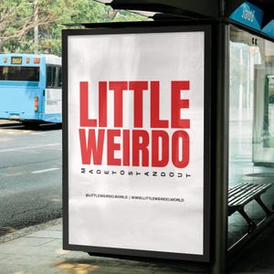Op de afbeelding: Een wit bushokje met een rode en witte afbeelding met de tekst "LITTLE WEIRDO MADE TO STAND OUT" en daaronder de tekst "@LITTLEWEIRDO.WORLD | WWW.LITTLEWEIRDO.WORLD".