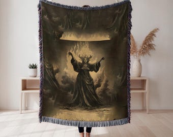 Puede incluir: Una manta tejida con una ilustración en tonos sepia de una figura con cabello de fuego y brazos extendidos. La obra de arte representa una escena dramática con nubes y un brillo dorado. La manta tiene un borde con flecos en tonos azules, morados y negros.