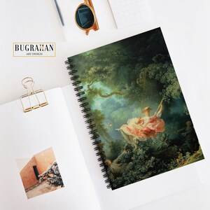 May include: A spiral bound notebook with a colorful painting of a woman on a swing in a lush green forest. The painting is a reproduction of a famous artwork.