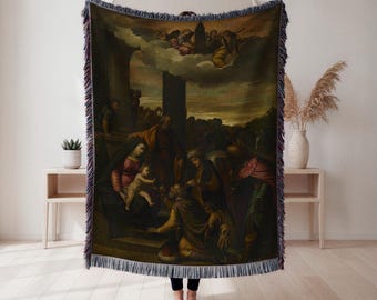 Op de afbeelding: Geweven sprei met een klassiek schilderij dat een religieuze scène met figuren in gewaden uitbeeldt. Het kunstwerk heeft een donker, gedempt kleurenpalet met een gedetailleerde weergave van mensen en engelen. De deken heeft een gefranjerde rand.