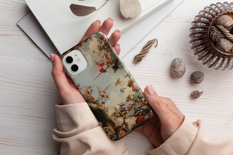 Puede incluir: Una funda de tel&eacute;fono blanca con una pintura colorida de &aacute;ngeles y una bandera roja. La funda tiene un recorte para el objetivo de la c&aacute;mara.