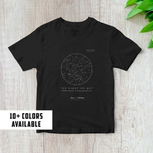 Puede incluir: Camiseta negra con un diseño de constelación de estrellas blancas y el texto "The Night We Met" con una cita y los nombres "Jane & Thomas". Más de 10 colores disponibles.
