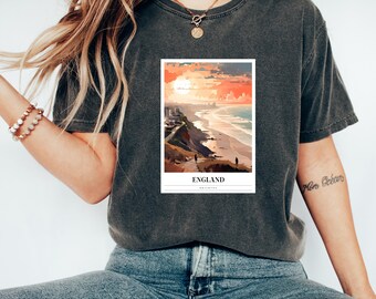 Könnte beinhalten: Ein dunkelgraues T-Shirt mit einem Grafikdruck eines Sonnenuntergangs über einem Strand in England. Die Grafik enthält auch den Text "ENGLAND" und "BRIGHTON".