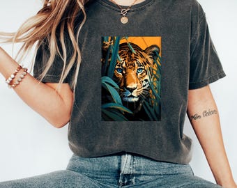May include: A dark gray t-shirt with a graphic print of a tiger's face peeking out from behind green leaves. The tiger has blue eyes and a yellow and orange striped coat.