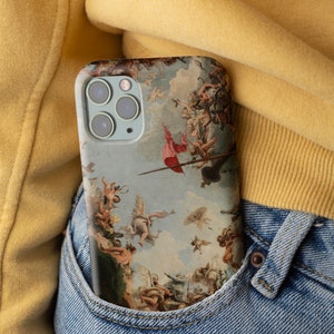 Puede incluir: Una funda de tel&eacute;fono azul con una pintura renacentista de &aacute;ngeles y figuras en el cielo. La funda est&aacute; en un bolsillo de mezclilla azul.