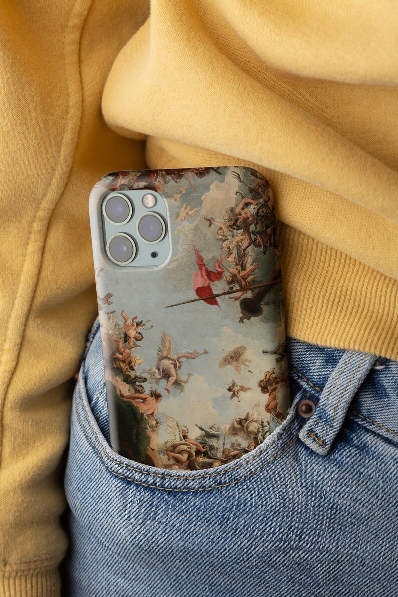 Puede incluir: Una funda de tel&eacute;fono azul con una pintura renacentista de &aacute;ngeles y figuras en el cielo. La funda est&aacute; en un bolsillo de mezclilla azul.