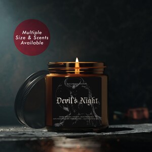 May include: A brown glass candle jar with a black label that reads "HALLOWEEN EDITION Devil's Night DARK WICKS | VEGAN | ECO-FRIENDLY 100% NATURAL SOY WAX BLEND | 100% COTTON WICK". The candle is lit and the flame is visible.