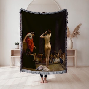 May include: A woven throw blanket featuring a classical painting depicting a nude figure before a crowd. The artwork showcases figures in robes and a dark background, with fringed edges.