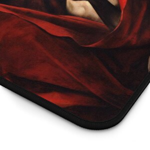 May include: Close-up of a red fabric with a textured surface. The fabric is folded and has a dark border.