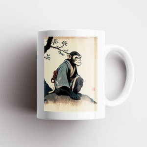 May include: White ceramic mug with a colorful illustration of a monkey wearing a blue robe and sitting on a rock. The monkey is looking to the right. The background is a light beige with a brown tree branch.
