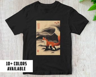 May include: Black t-shirt featuring a graphic print of a red fox standing in a mountain landscape. The fox has a long, bushy tail. The text "10+ COLORS AVAILABLE" is printed at the bottom of the image.