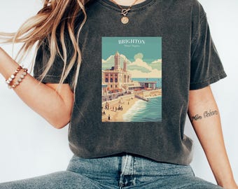 Könnte beinhalten: Ein dunkelgraues T-Shirt mit einem Vintage-Grafikdruck von Brighton, England. Die Grafik zeigt ein Gebäude mit einem Strand und dem Meer im Hintergrund. Der Text "Brighton" und "Vereinigtes Königreich" ist auf der Grafik gedruckt.