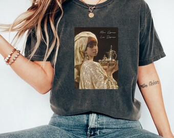 Può includere: T-shirt grigio scuro con un dipinto in stile vintage di una donna che tiene in mano un vassoio con una teiera e delle tazze. Il testo "More Espresso, Less Depresso" è stampato sulla maglietta. La maglietta è realizzata in un materiale morbido e confortevole.