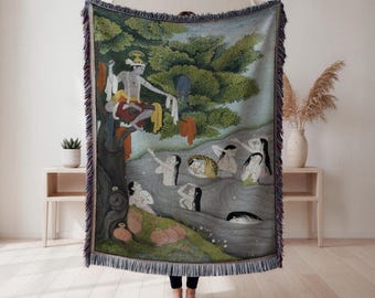 May include: A woven throw blanket with a detailed illustration of a scene with figures in a river and a person in a tree. The artwork has a muted colour palette with green, blue, and red accents. The blanket has a fringed edge.
