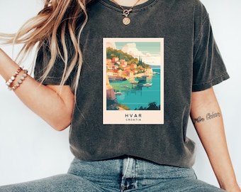 Op de afbeelding: Een donkergrijs T-shirt met een vintage-stijl grafische afbeelding van een kuststad met de tekst "HVAR CROATIA".