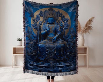 Könnte beinhalten: Eine blaue Decke mit einer detaillierten Illustration einer sitzenden Buddha-Figur mit goldenen Akzenten. Das Kunstwerk ist vor einem blauen Hintergrund mit wolkenartigen Formationen platziert. Die Decke hat einen Fransenrand.
