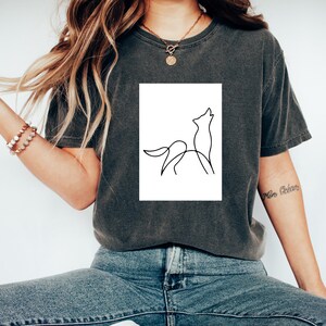May include: A dark gray t-shirt with a white square graphic of a single line drawing of a wolf howling at the moon.