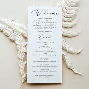 May include: A vertical white wedding welcome card with black serif and script text. The card lists event details for Taylor and Harrison, including a welcome party, ceremony, and reception schedule. The text is printed on a smooth white cardstock.