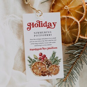 May include: A white tag with the text "Holiday Simmering Potpourri" and a watercolour illustration of dried oranges, cinnamon sticks, and pine needles. The text "Handmade by Madison" is also on the tag.