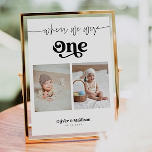May include: A gold-framed sign with the text "When we were one" in black cursive script. The number "one" is in a large, stylized font. Two photos of babies are below the text, one of a baby boy wearing a hat and the other of a baby girl wearing a bunny ear headband. The text "Oliver & Madison 08.26.20XX" is below the photos.