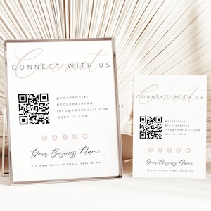 May include: Two white signs with black text and a QR code. The larger sign says "Connect with us" and includes social media handles, an email address, and a website. The smaller sign says "Connect with us" and includes the same information. Both signs have the text "Your Business Name" and an address.