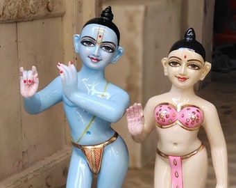 May include: Two small, hand-painted figurines of deities. The male figure is blue with gold accents and a red and gold loincloth. The female figure is white with gold accents and a pink and gold bodice and skirt.