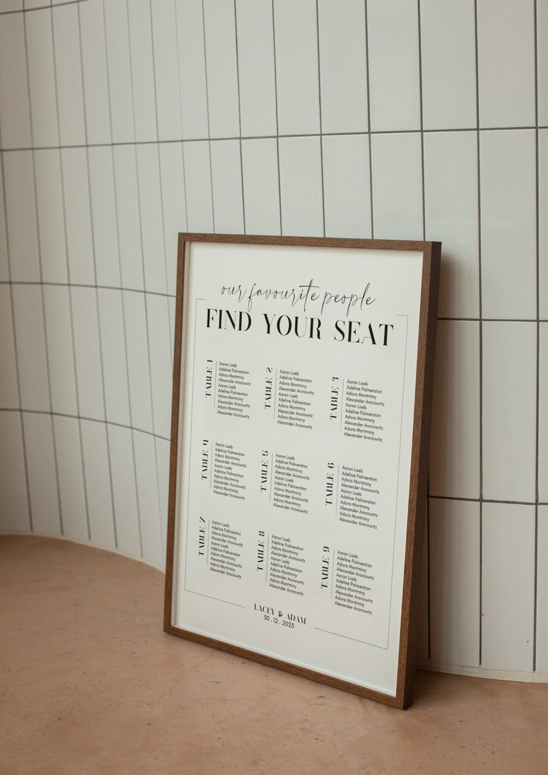 May include: A white seating chart with a brown wooden frame. The chart has the text "our favourite people FIND YOUR SEAT" at the top. The chart lists names and table numbers for a wedding reception. The bottom of the chart reads "LACEY & ADAM 30.12.2023".