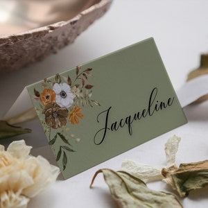 Może przedstawiać: Zielona karta miejsca z kwiatowym wzorem i imieniem Jacqueline napisanym czarnym, ozdobnym pismem.