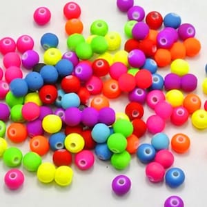 May include: A large assortment of colorful round beads. The beads are made of plastic and have a smooth, glossy finish. The beads are in a variety of bright colors, including red, orange, yellow, green, blue, purple, and pink.