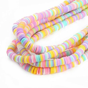 May include: A strand of colourful round polymer clay beads. The beads are layered in a rainbow pattern of pink, yellow, white, and blue.