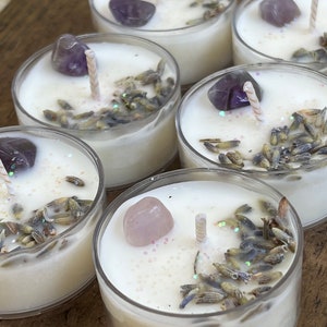 May include: Six clear glass tea light holders with white wax and lavender buds. Each holder contains a small amethyst or rose quartz crystal.